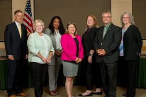 The seven board of education members standing in teh board room